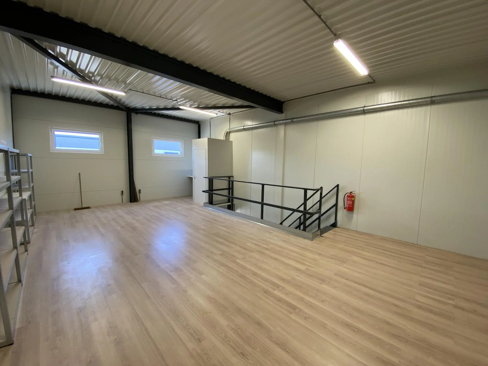 Open ruimte met laminaatvloer en trap in een bedrijfsruimte aan de Aalsmeerderweg.