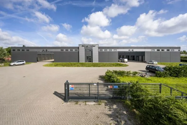 Voorgevel van het Storage Center Aalsmeer aan de Aalsmeerderweg met meerdere ingangen en geparkeerde auto's.