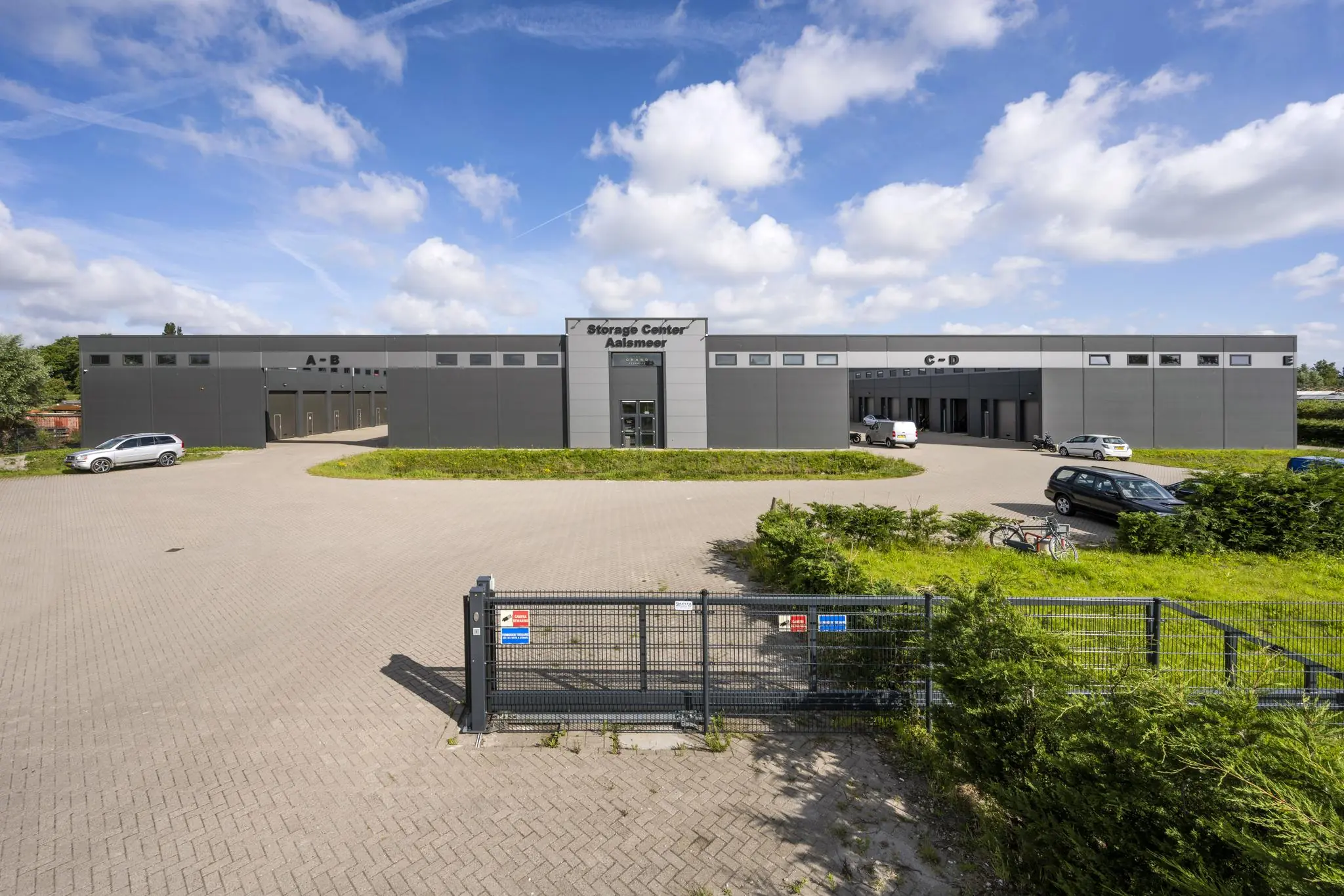 Voorgevel van het Storage Center Aalsmeer aan de Aalsmeerderweg met meerdere ingangen en geparkeerde auto's.