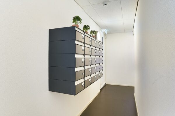 Wand met metalen brievenbussen in een lichte gang van het appartementencomplex Middenburcht.