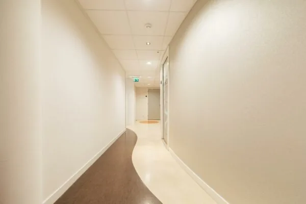 Lichte, modern ontworpen gang in zorginstelling Middenburcht met golvend patroon in de vloer.