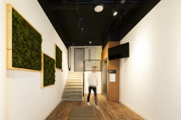 Moderne entreehal van Middenburcht met trap, lift, muurdecoratie van mos en een plafond met zwarte afwerking.