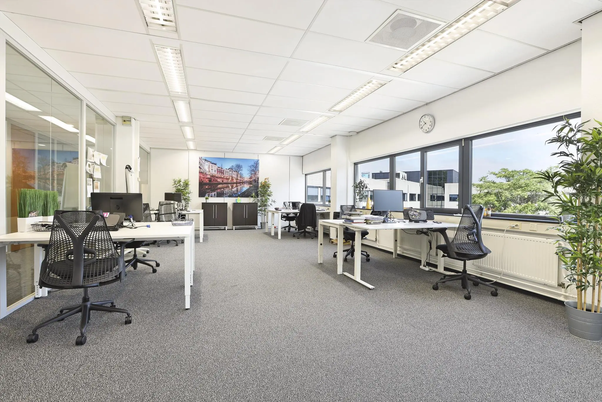 Modern en licht kantoor aan de Winthontlaan met open werkplekken, grote ramen en een foto van de Utrechtse grachten aan de wand.