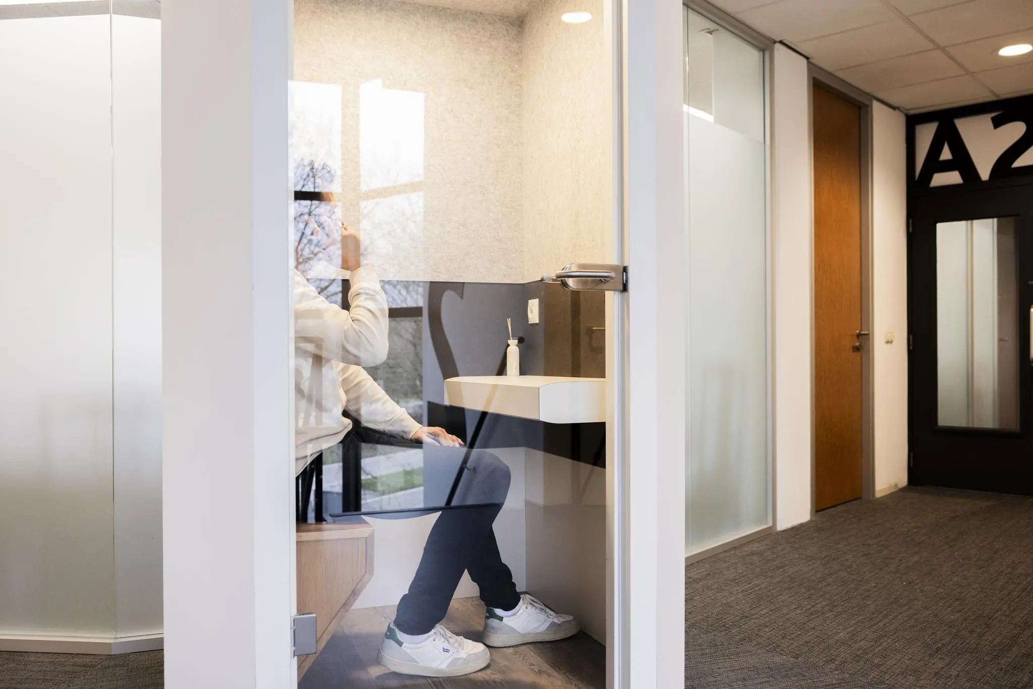 Persoon voert een telefoongesprek in een kleine belruimte aan de Winthontlaan.