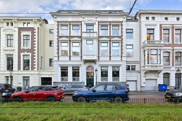 Voorgevel van een monumentaal pand aan de Koninginnegracht met geparkeerde auto's ervoor.