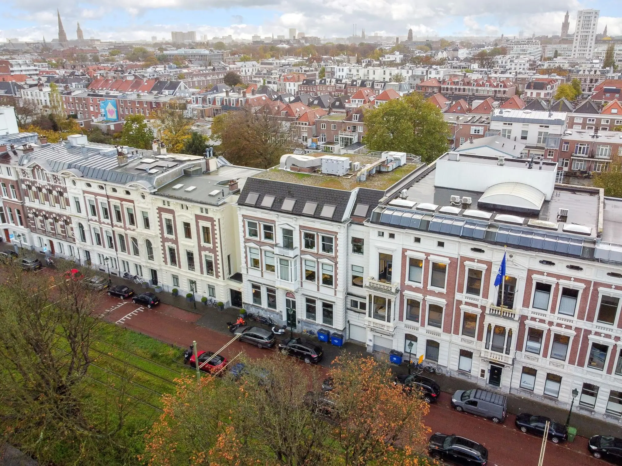 Luchtfoto van de Koninginnegracht in Den Haag met historische gebouwen en geparkeerde auto's langs de straat.