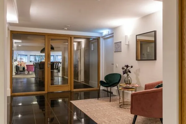 Stijlvol ingerichte wachtruimte aan de Koninginnegracht met moderne meubels, glazen deuren en warme verlichting.