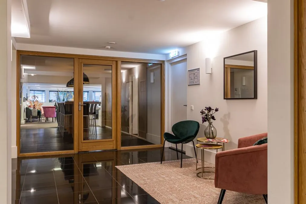 Stijlvol ingerichte wachtruimte aan de Koninginnegracht met moderne meubels, glazen deuren en warme verlichting.