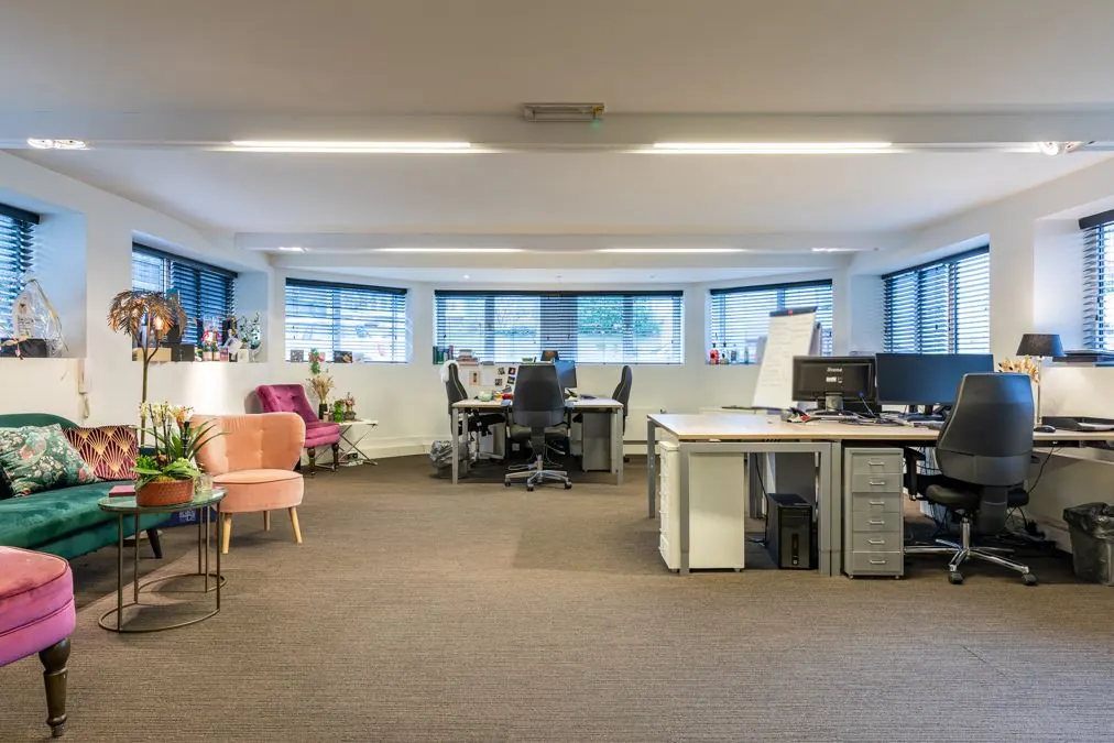 Modern kantoorinterieur aan de Koninginnegracht met bureaus, computers en kleurrijke zithoeken.