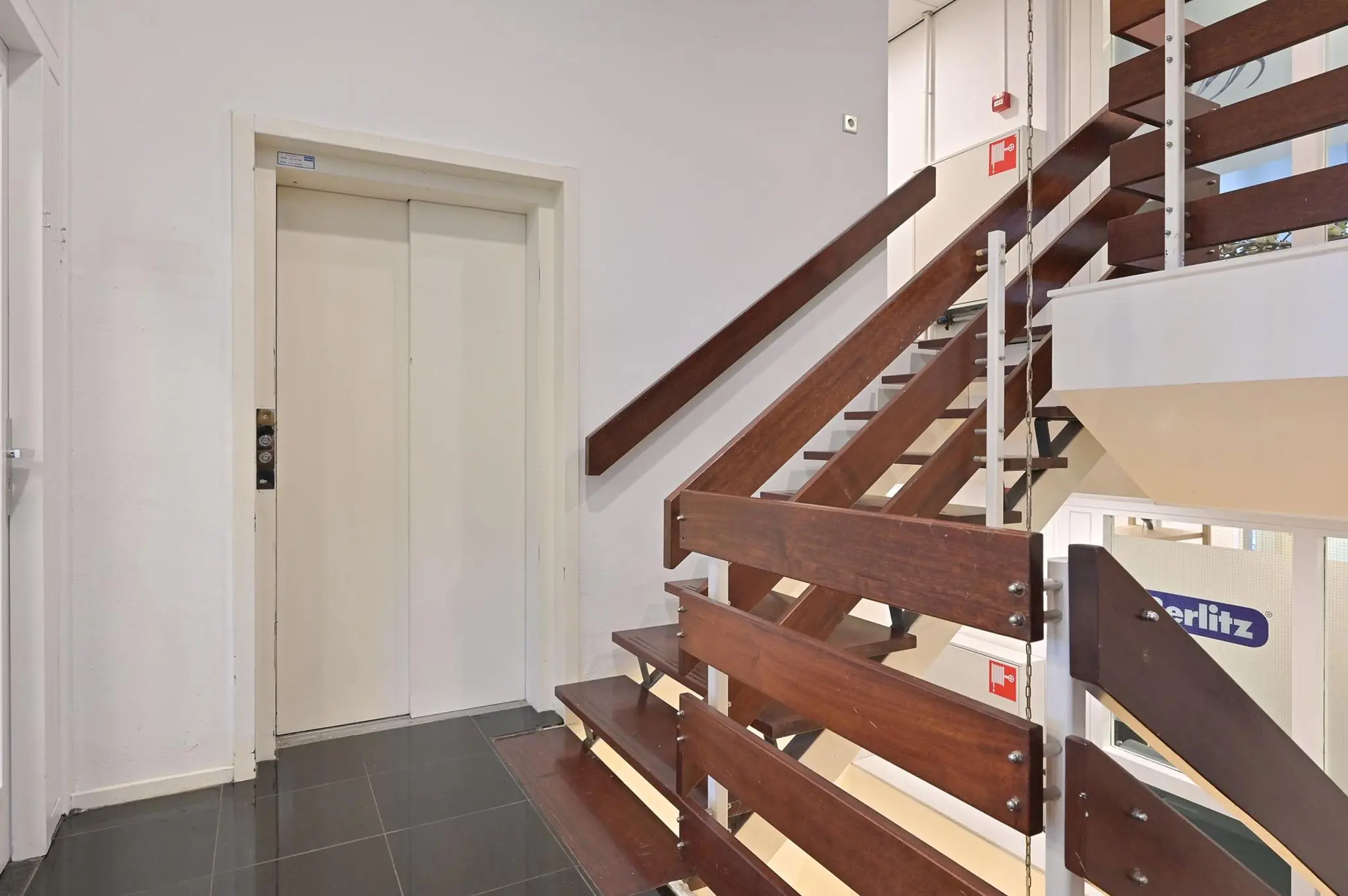 Trappenhuis met houten trap en lift in een kantoorpand aan de Koninginnegracht.