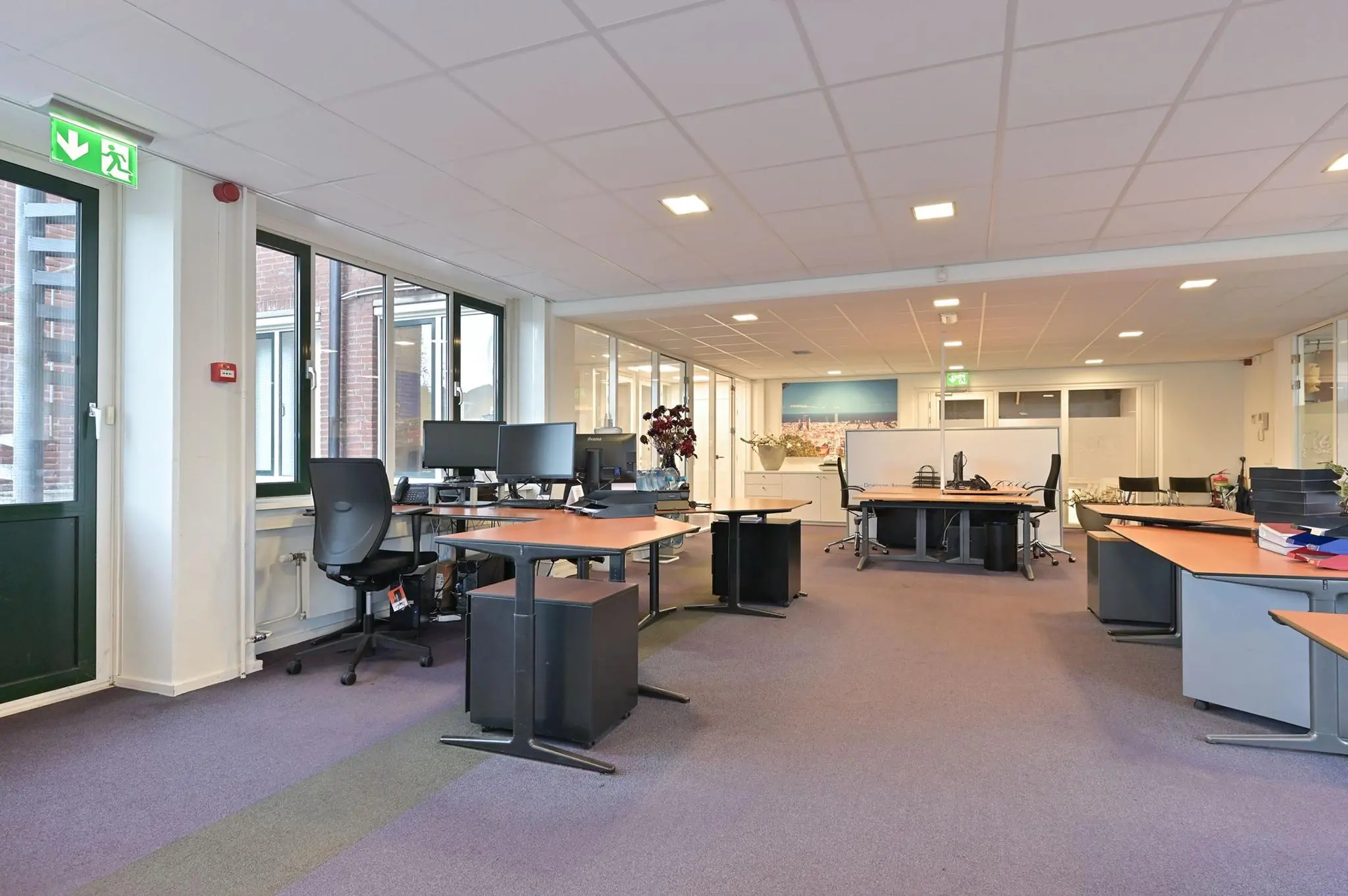 Modern kantoorinterieur aan de Koninginnegracht met meerdere werkplekken en grote ramen.