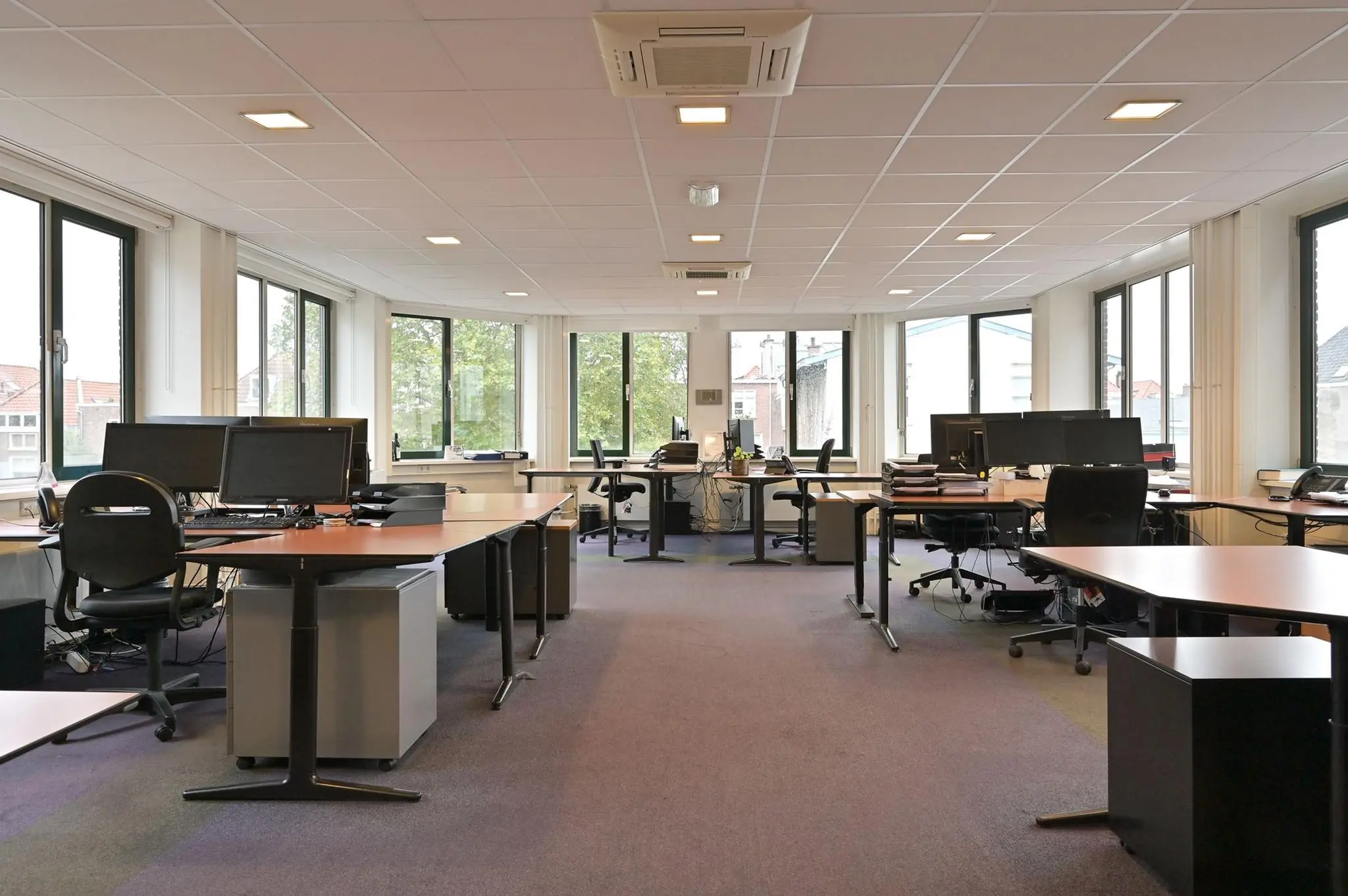 Ruim, licht kantoorgebouw aan de Koninginnegracht met meerdere bureaus en grote ramen.