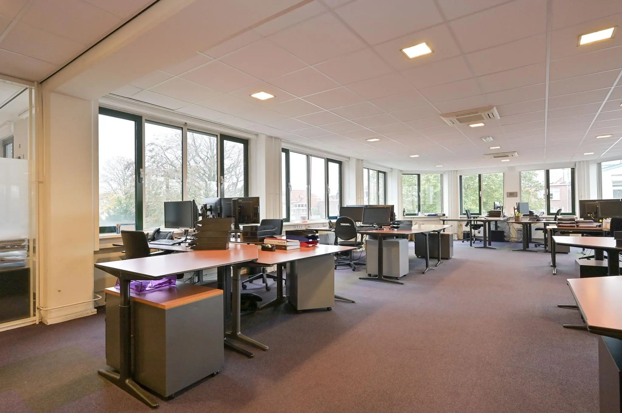 Ruime en lichte kantoorruimte aan de Koninginnegracht met meerdere werkplekken en grote ramen.