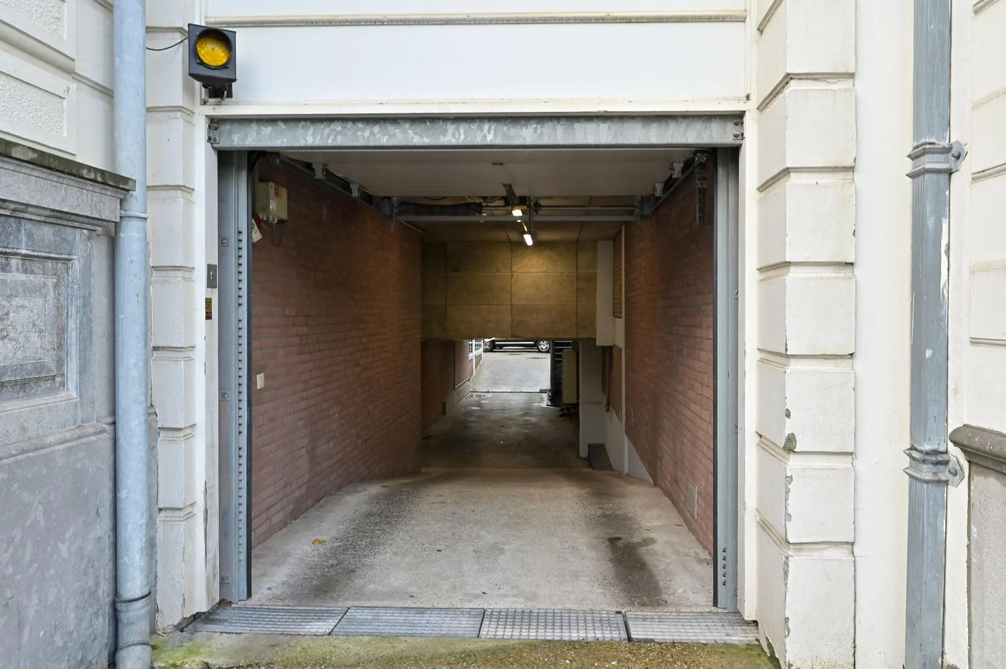 Ingang van een parkeergarage aan de Koninginnegracht met een geel waarschuwingslicht boven de doorgang.