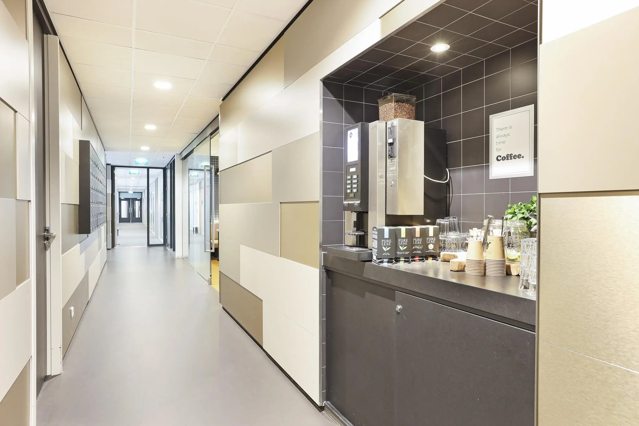 Koffiecorner met automaat en glazen in een moderne gang aan de Winthontlaan.