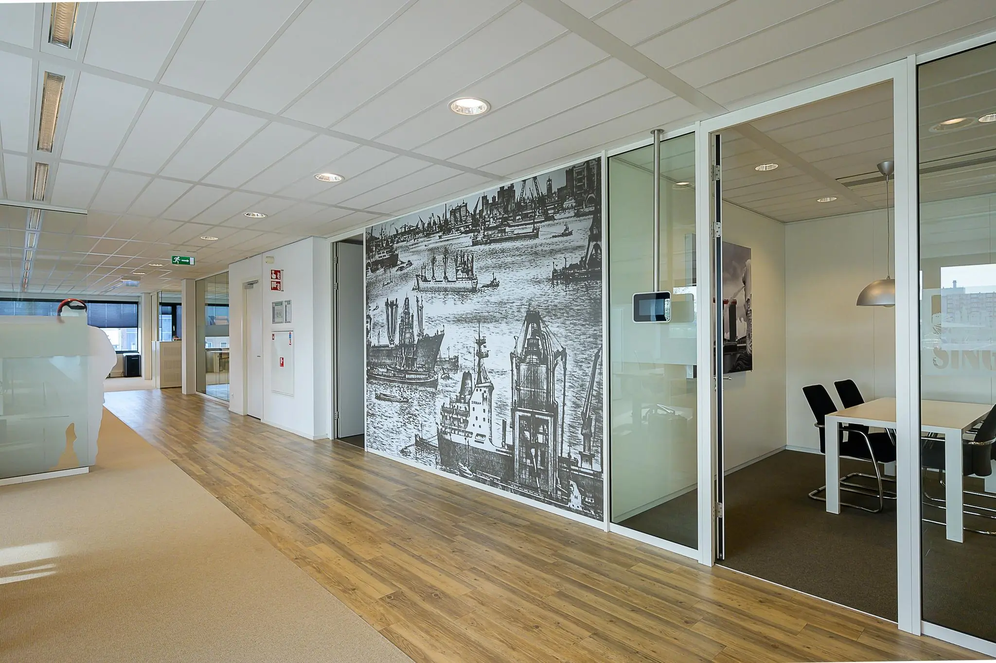 Moderne kantoorruimte aan de Willingestraat met glazen vergaderruimte en een wanddecoratie van een havenstad.
