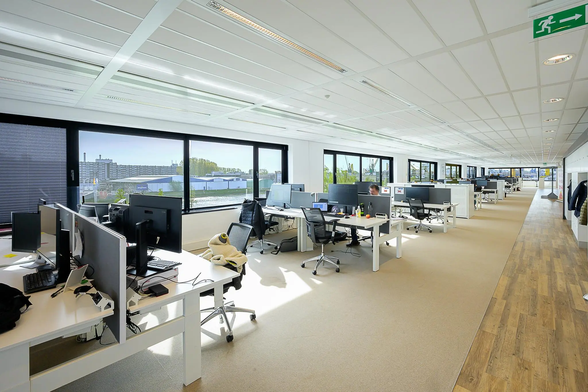 Modern open kantoor met werkplekken, grote ramen en uitzicht op de Willingestraat in een lichte, ruime omgeving.