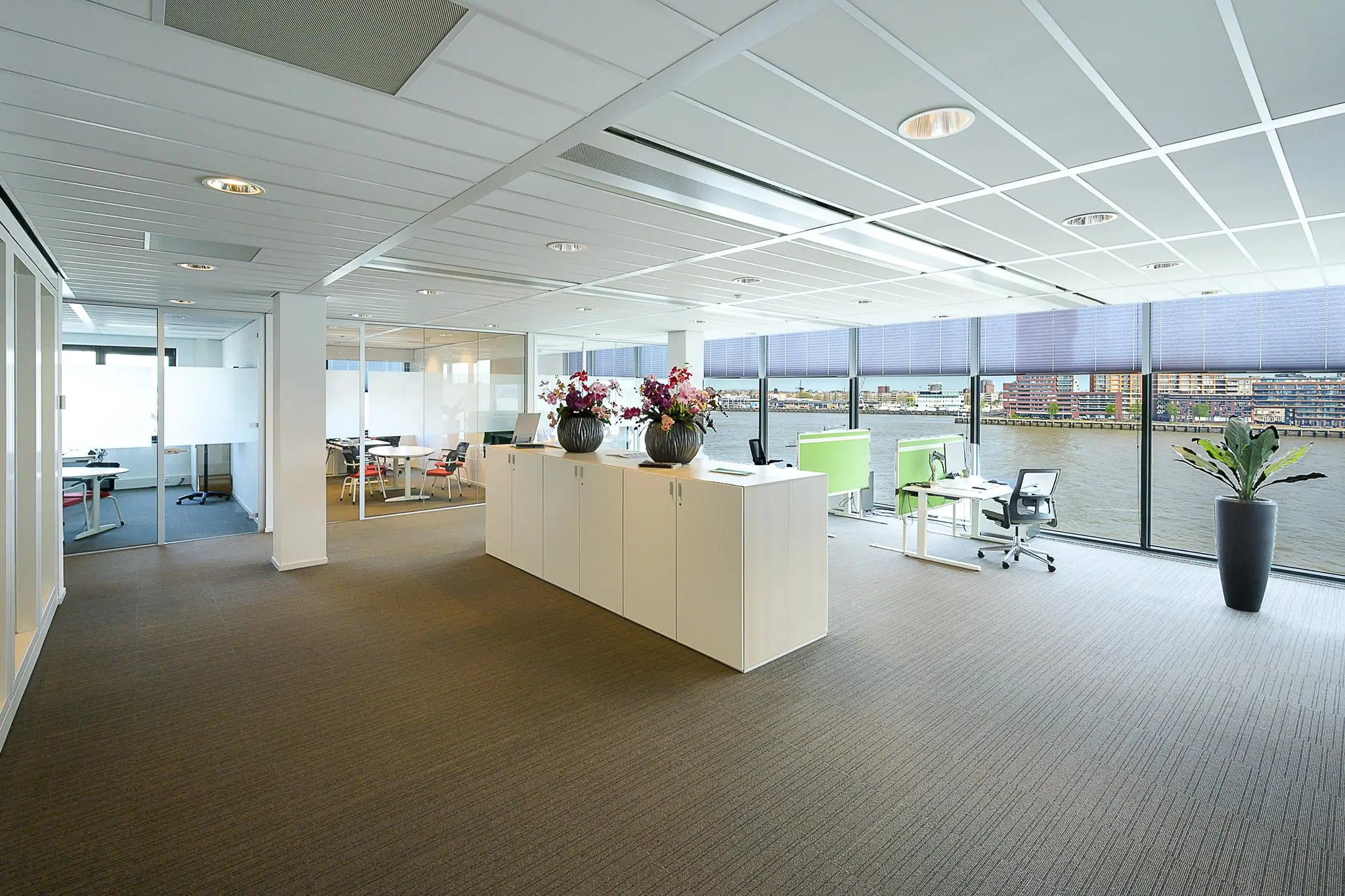 Modern kantoorinterieur aan de Willingestraat met glazen wanden, werkplekken en uitzicht op het water.