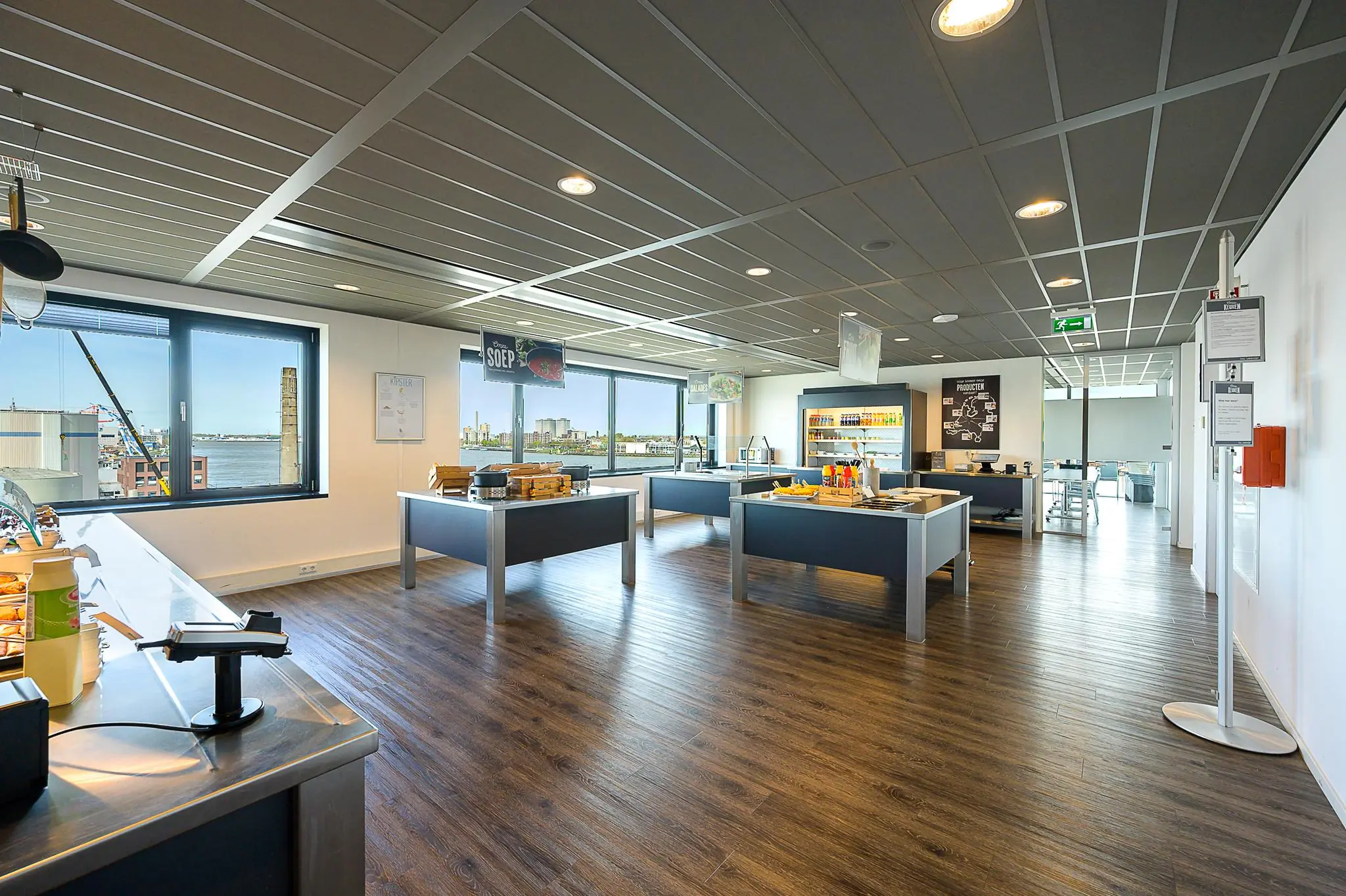 Moderne bedrijfskantine aan de Willingestraat met uitzicht op de stad en meerdere zelfbedieningsstations.