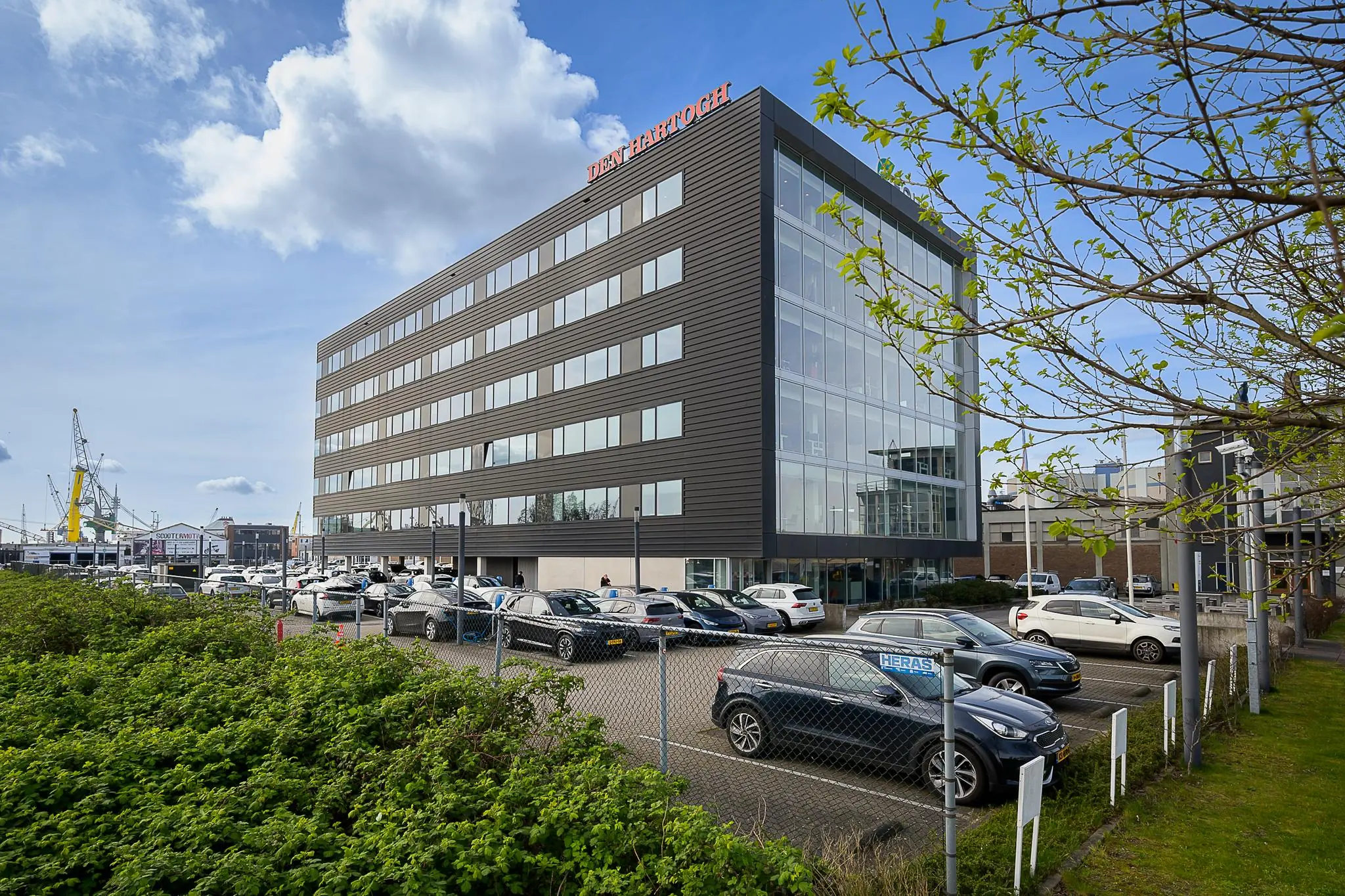 Kantoorpand van Den Hartogh aan de Willingestraat met parkeerruimte op de voorgrond.