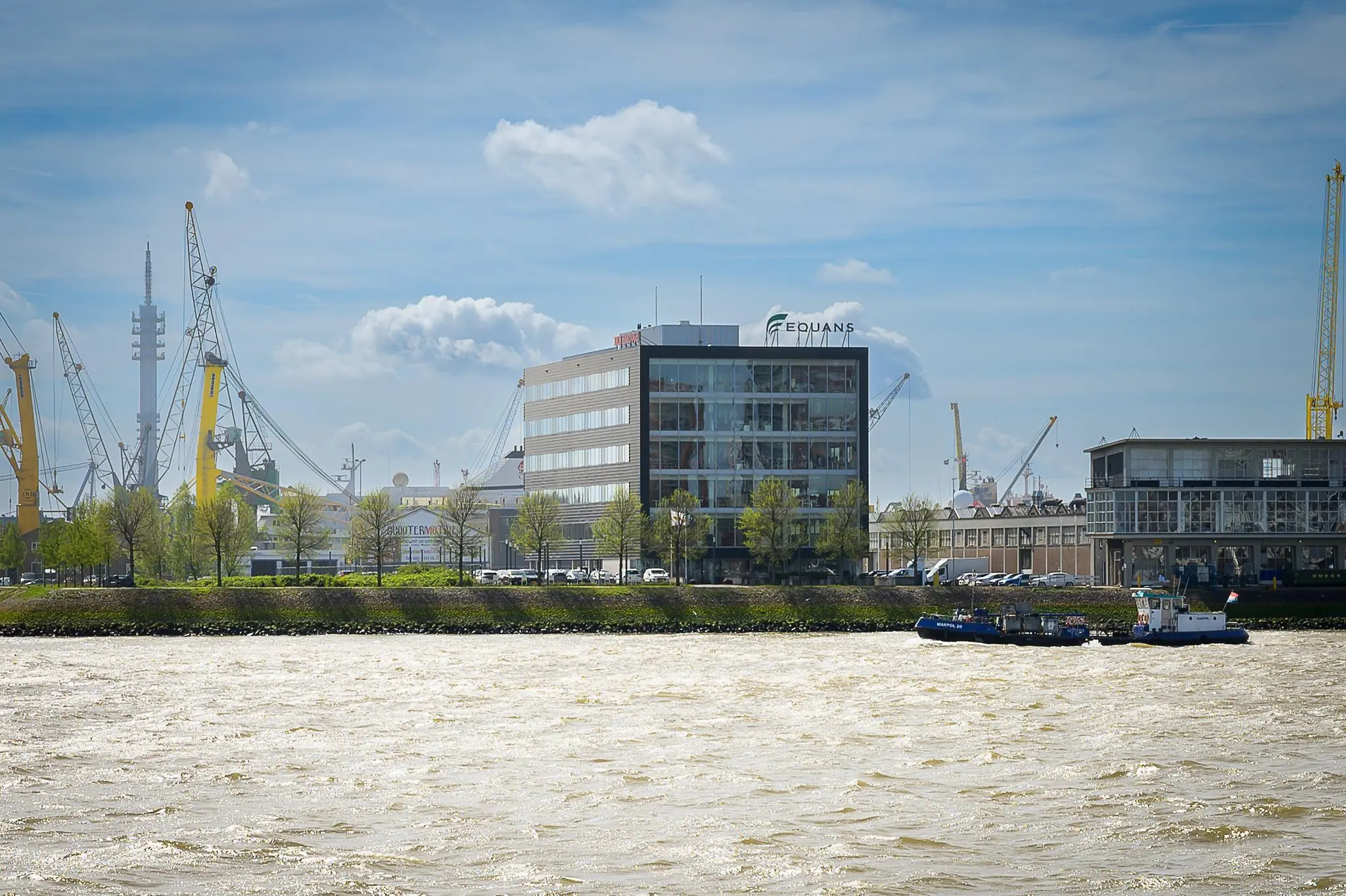 Kantoorgebouw van Equans aan de Willingestraat met uitzicht op de haven en een passerend schip op de voorgrond.