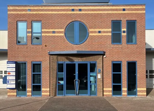 Vooraanzicht van een modern bakstenen kantoorgebouw aan de Bergveste 2 met blauwe kozijnen en een ronde raampartij.