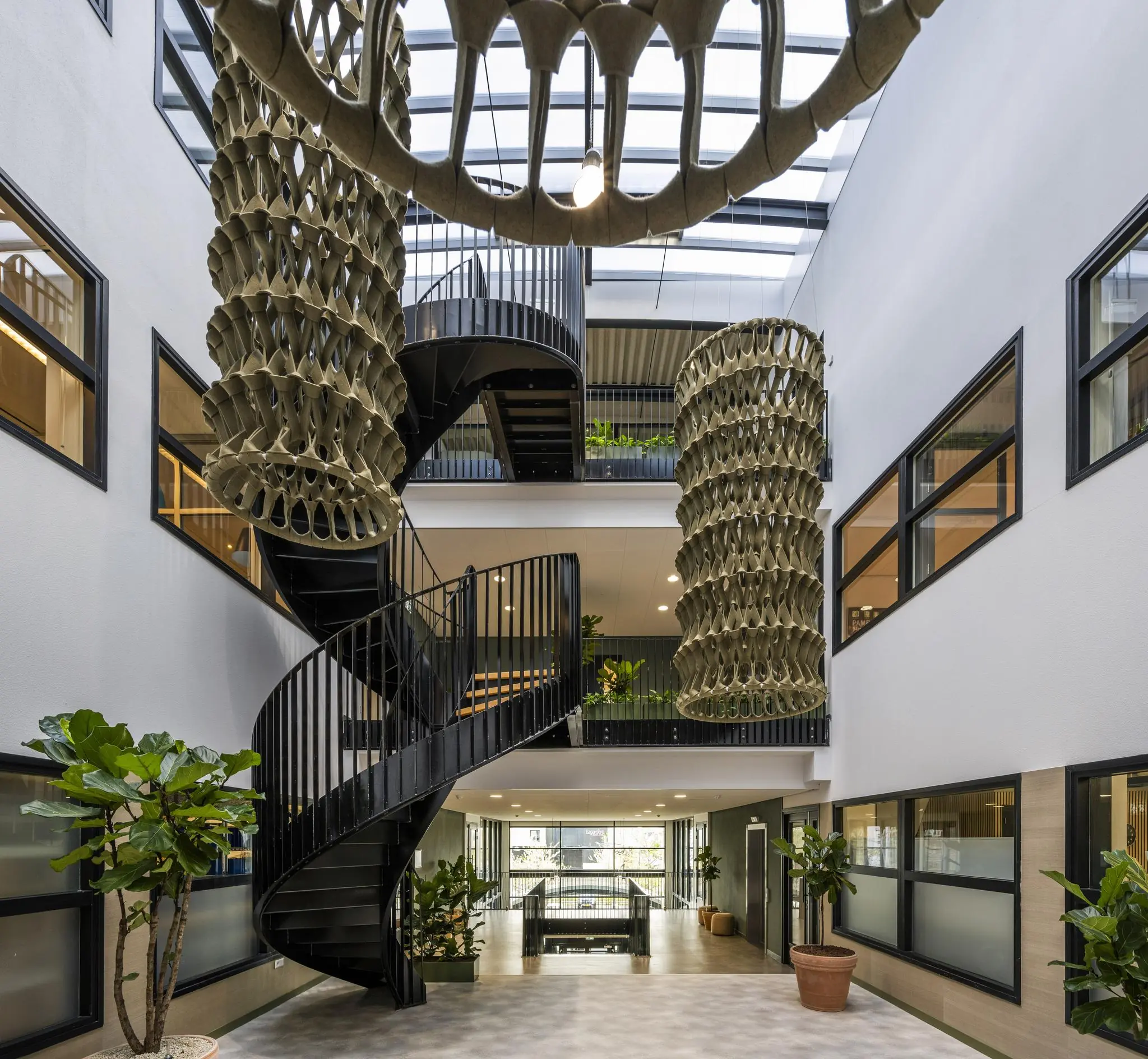 Moderne binnentuin met zwarte wenteltrap, hangende organische sculpturen en veel natuurlijke lichtinval aan de Singaporestraat.