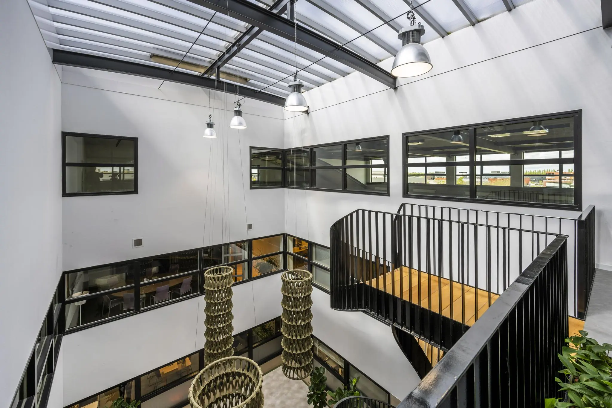 Moderne kantoorruimte aan de Singaporestraat met een open vide, metalen trap, hanglampen en grote ramen.