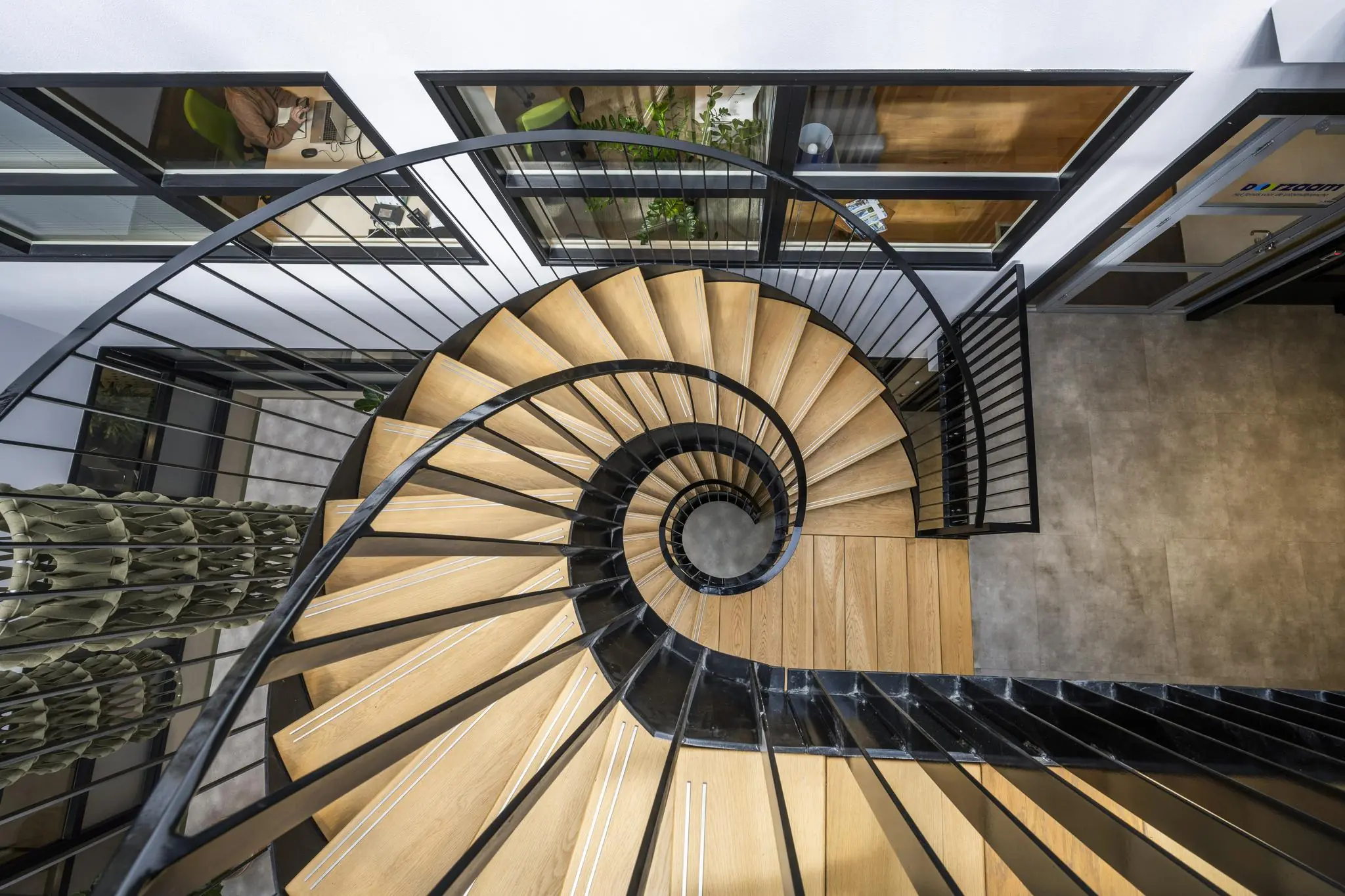 Wenteltrap met houten treden en zwart metalen balustrade in een modern kantoorgebouw aan de Singaporestraat.