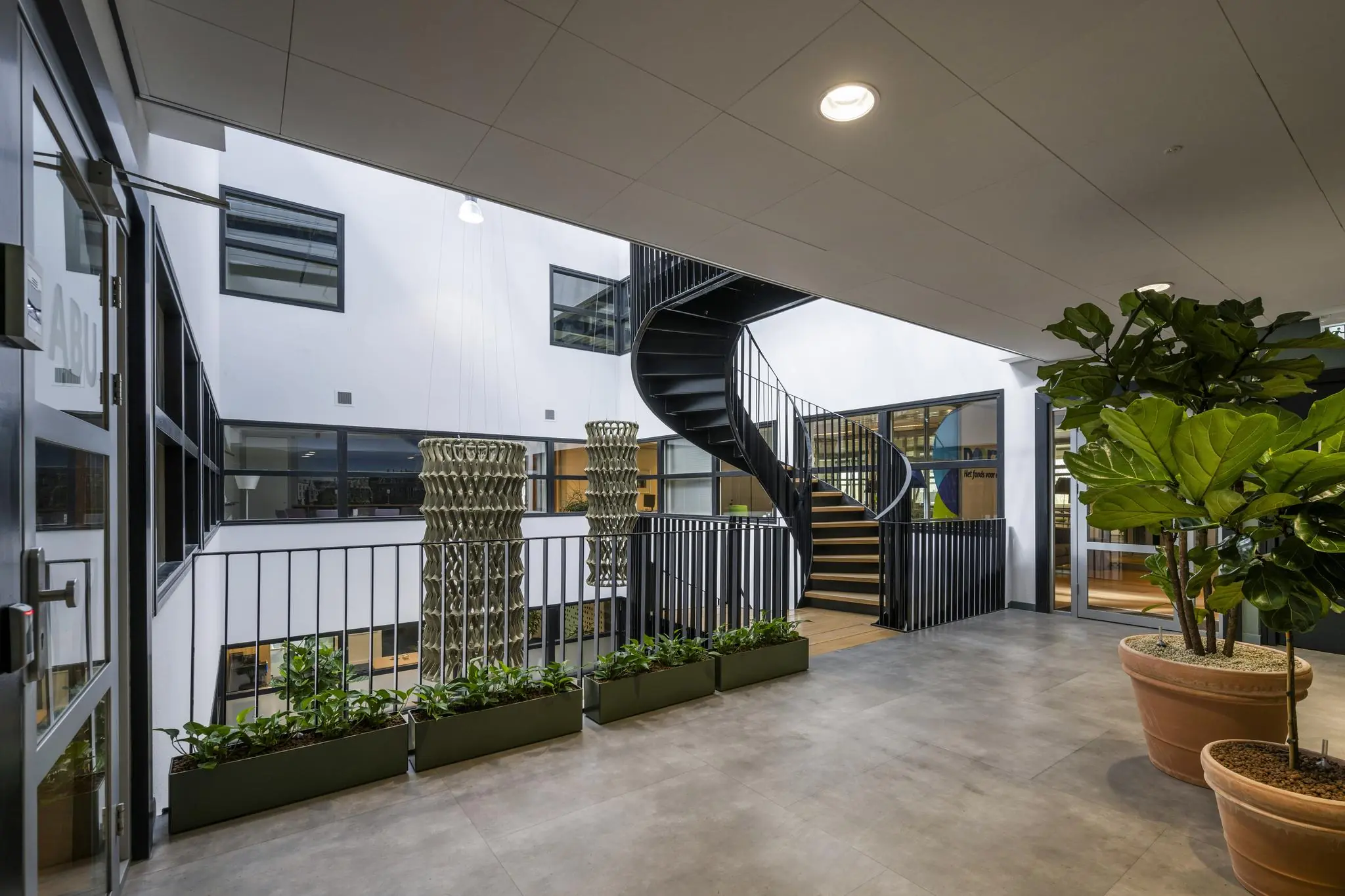 Moderne binnentuin met plantenbakken, wenteltrap en uitzicht op kantoren aan de Singaporestraat.