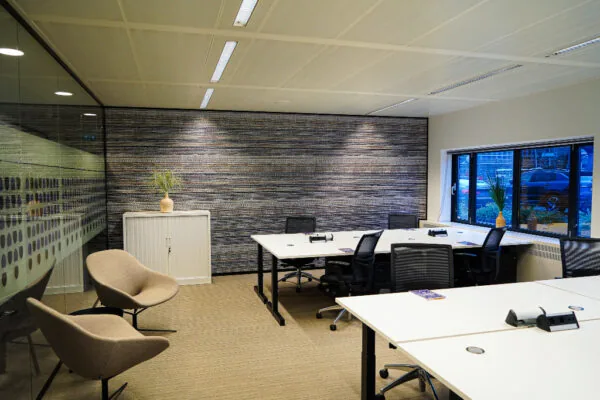 Moderne kantoorruimte aan het Prins Bernhardplein met werkplekken, vergaderstoelen en grote ramen met uitzicht op geparkeerde auto's.