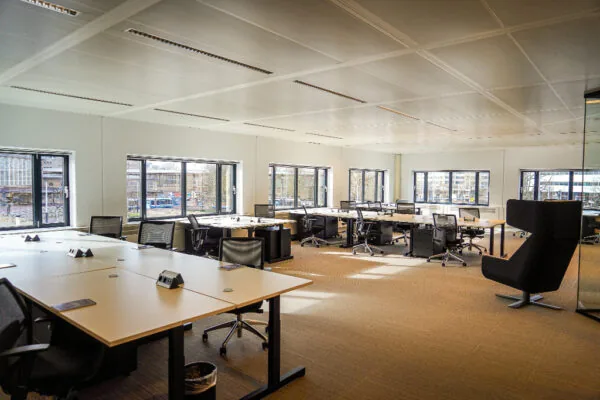 Ruim, modern kantoor met werkplekken en grote ramen aan het Prins Bernhardplein.