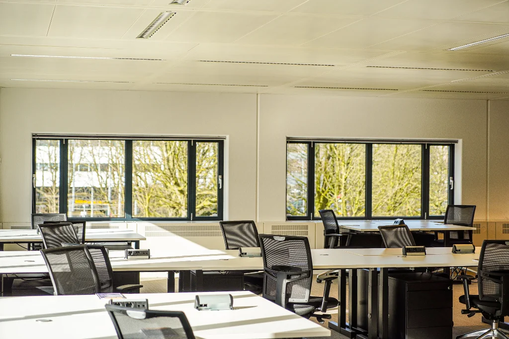 Licht en modern kantoor met werkplekken en uitzicht op bomen aan het Prins Bernhardplein.
