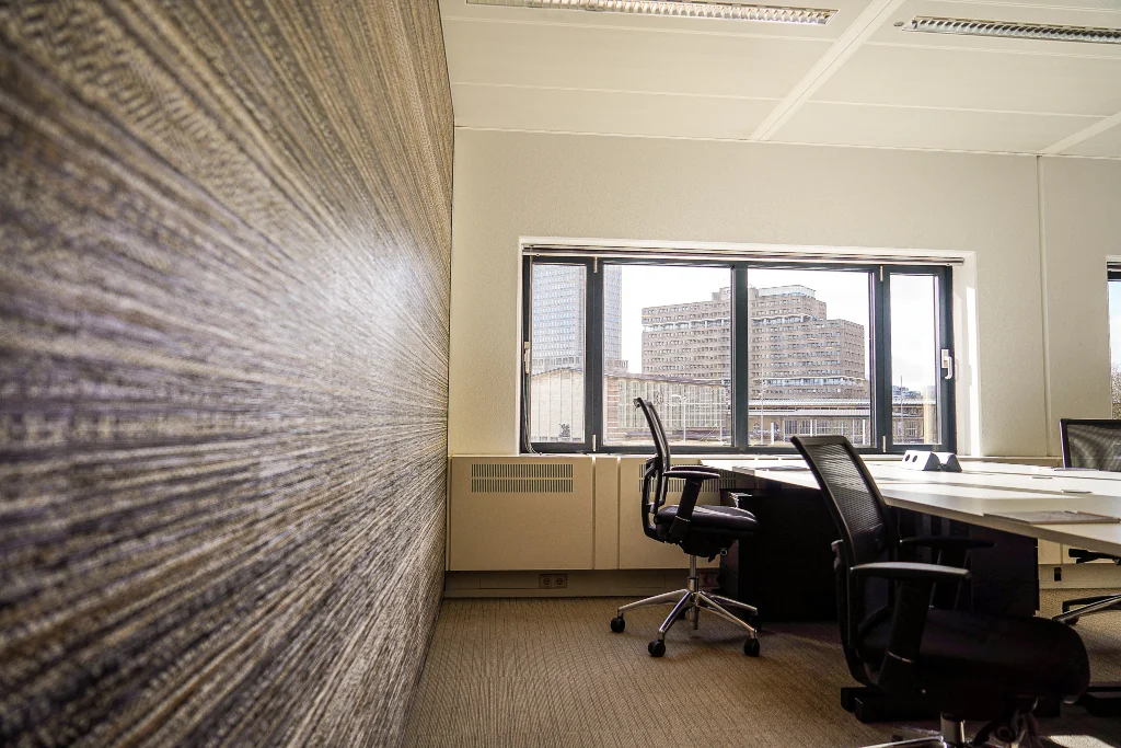 Modern kantoor met bureaustoelen en uitzicht op gebouwen aan het Prins Bernhardplein in Amsterdam.