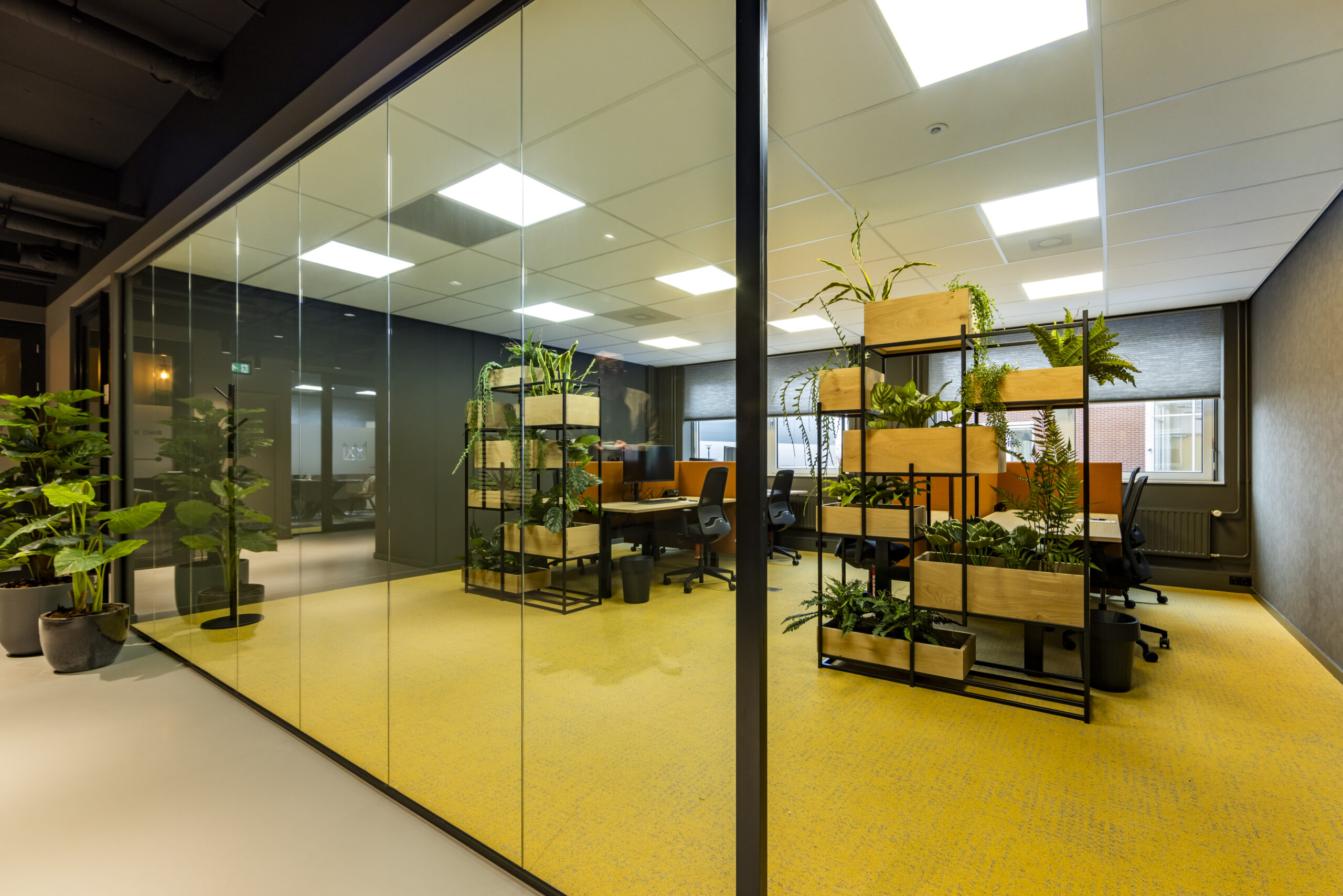 Een moderne kantoorruimte met veel groen en glazen wanden.