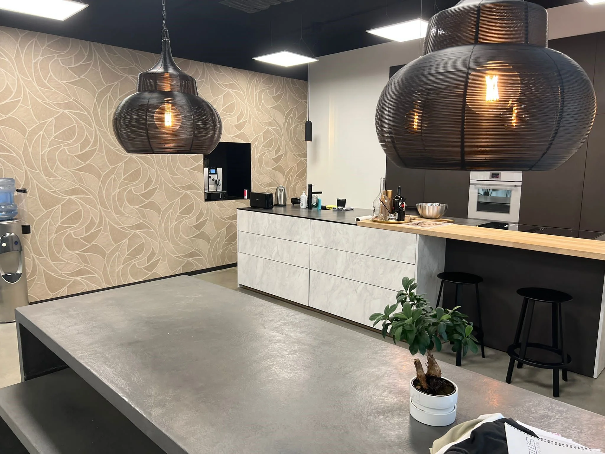 Moderne keuken in Frankfurtstraat met betonnen tafel, sierlijke hanglampen en een decoratieve plantenbak.