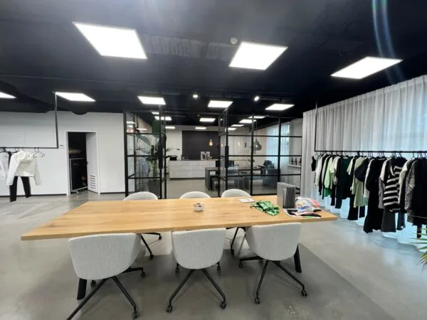 Moderne vergaderruimte aan de Frankfurtstraat met een houten tafel, designstoelen en kledingrekken langs de wand.