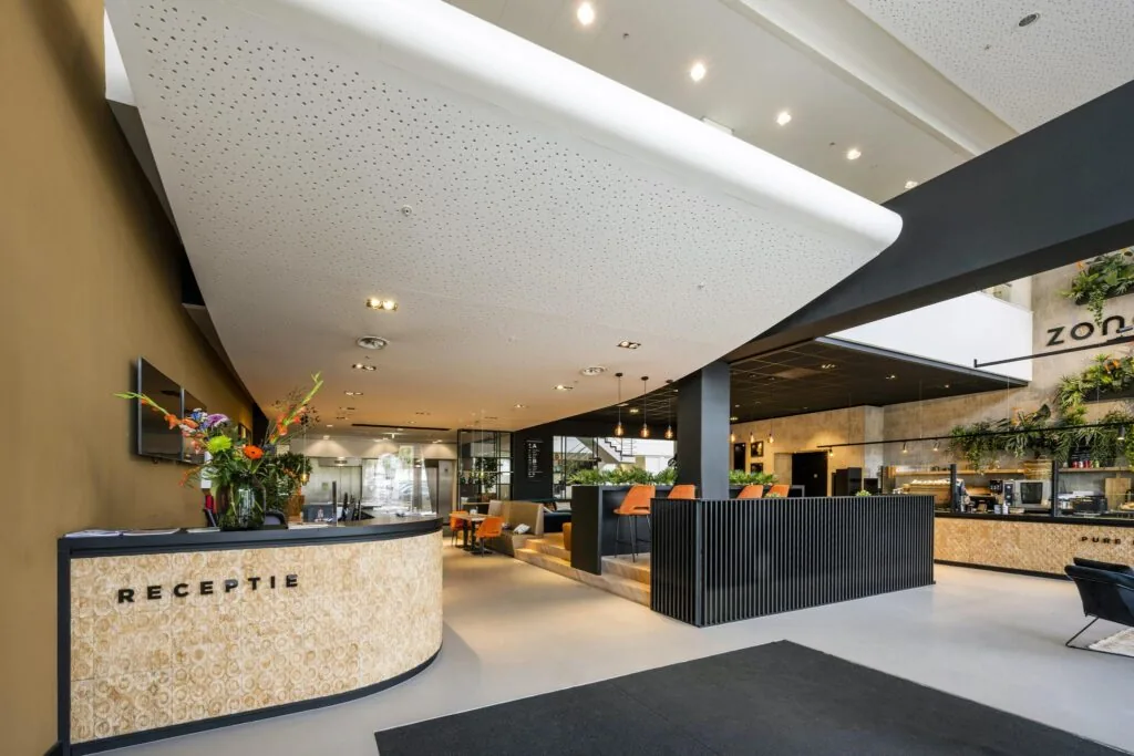 Moderne ontvangsthal aan de Laarderhoogtweg met receptiebalie, zitgedeelte en groene wanddecoratie.