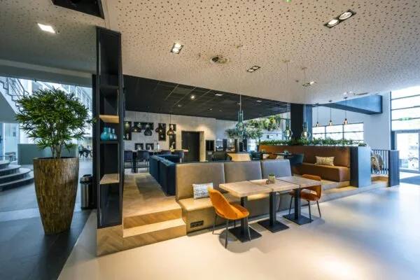 Moderne en sfeervolle lounge- en werkruimte aan de Laarderhoogtweg met zitbanken, tafels en hanglampen.