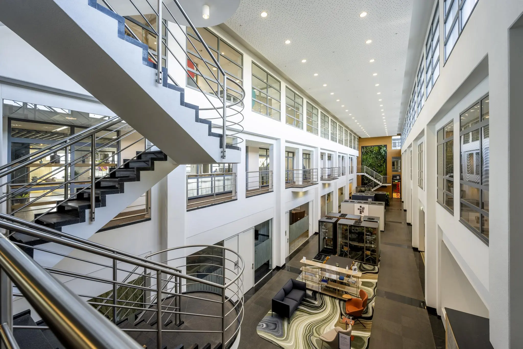 Moderne kantoorlobby aan de Laarderhoogtweg met open werkplekken, glazen wanden en een opvallend trappenhuis.