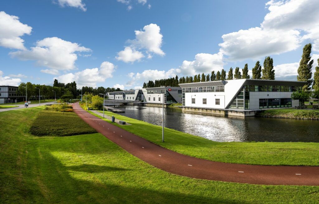 Modern kantoorgebouw aan het water aan de Frankfurtstraat in een groene, parkachtige omgeving met fietspad.