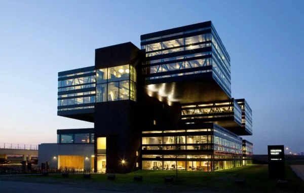 Modern kantoorgebouw Creative Valley aan de Orteliuslaan, met opvallende glazen gevels en uitstekende bouwdelen, verlicht in de avondschemering.