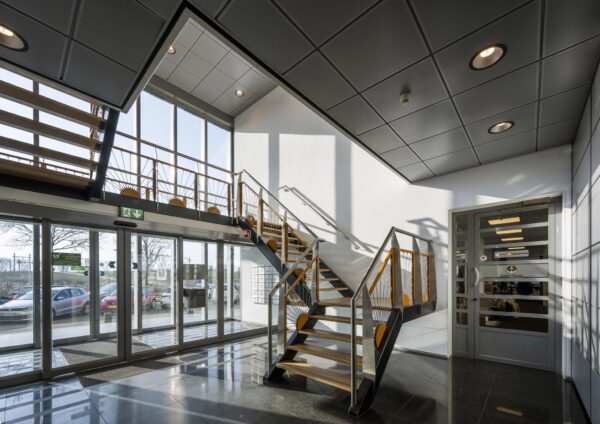 Moderne entreehal aan de Joan Muyskenweg met glazen schuifdeuren, trap met houten leuningen en veel daglicht.