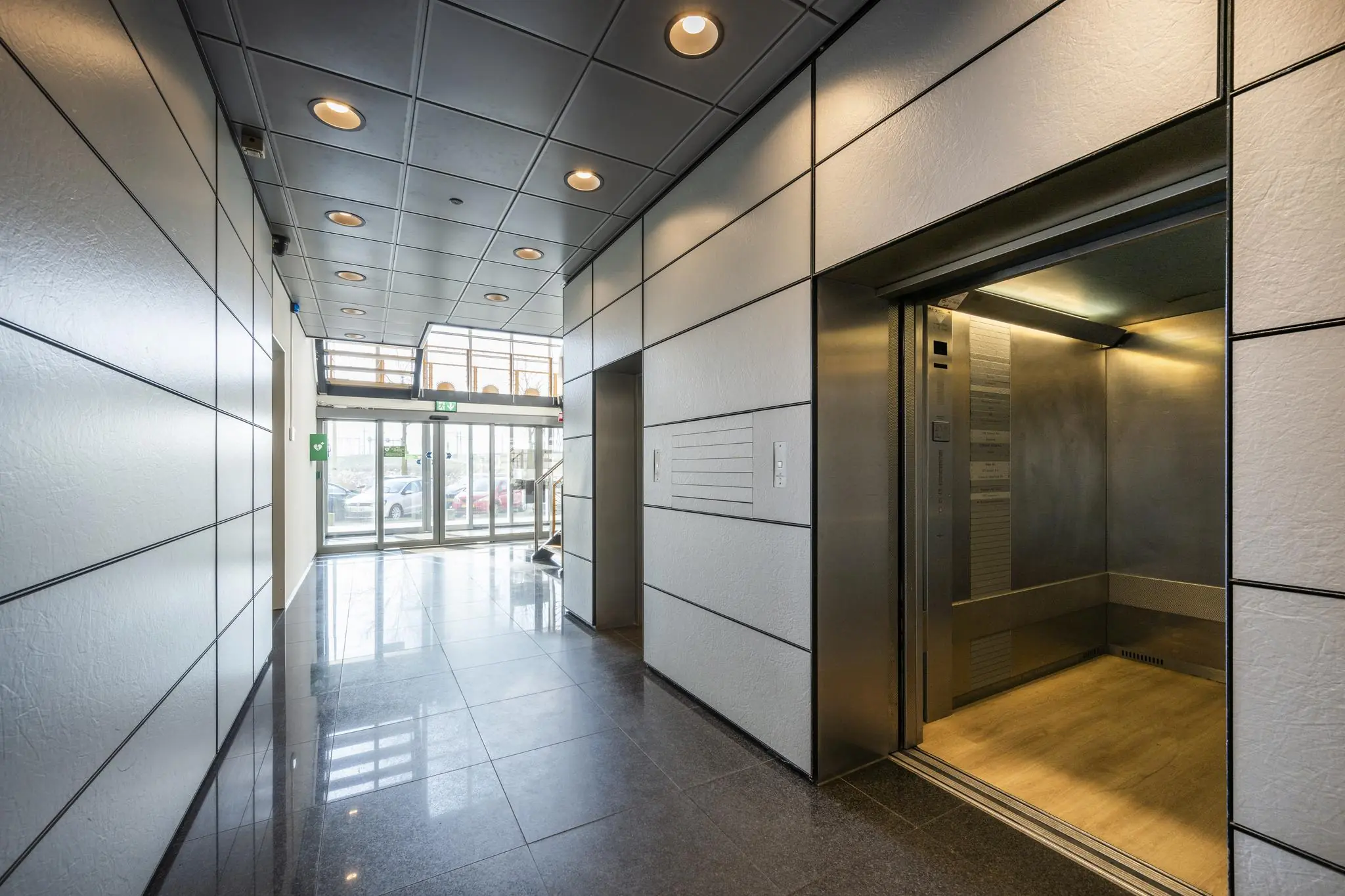 Moderne entreehal met openstaande lift in een kantoorgebouw aan de Joan Muyskenweg.