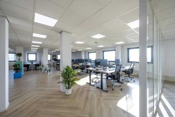 Moderne, lichte kantoortuin aan de Joan Muyskenweg met werkplekken, bureaustoelen en veel natuurlijke lichtinval.