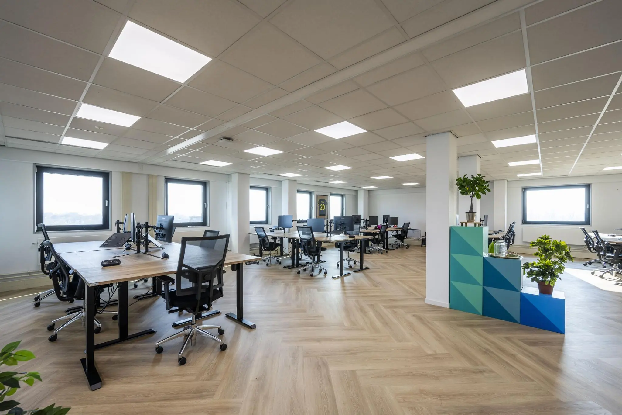 Modern en ruim kantoorinterieur aan de Joan Muyskenweg met werkplekken, houten vloer en veel daglicht.