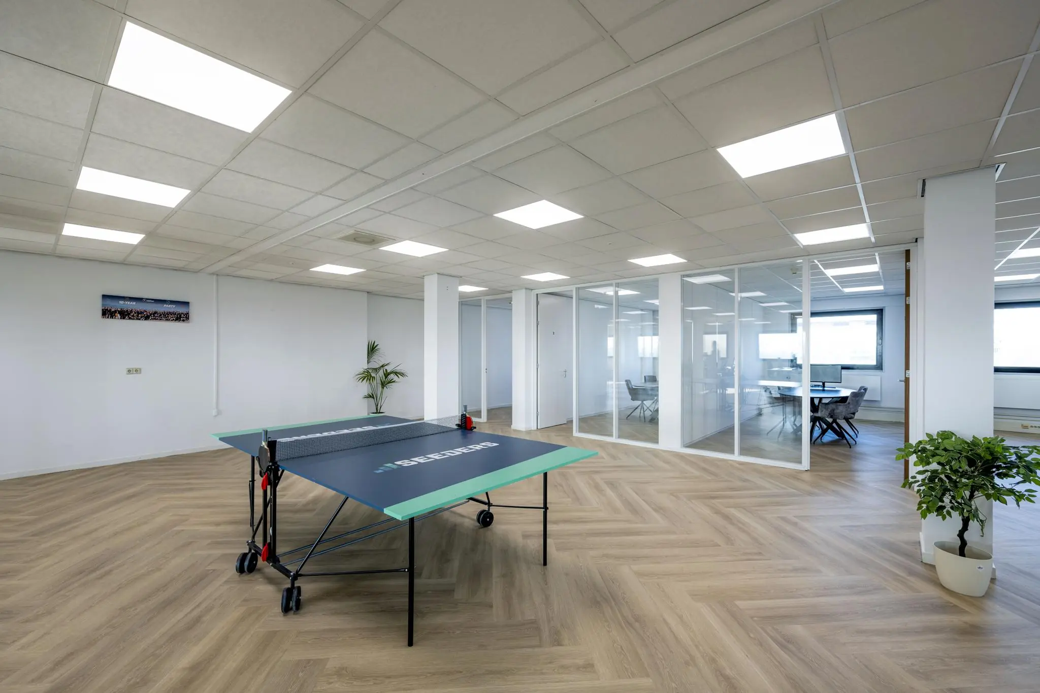 Moderne kantoorruimte aan de Joan Muyskenweg met glazen vergaderruimtes en een tafeltennistafel.