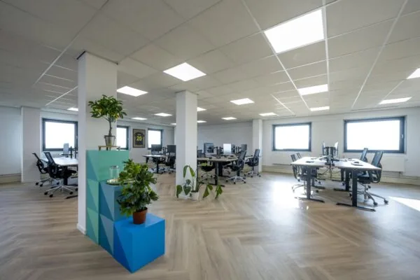 Modern en licht kantoorinterieur aan de Joan Muyskenweg met flexplekken, planten en ergonomische bureaustoelen.