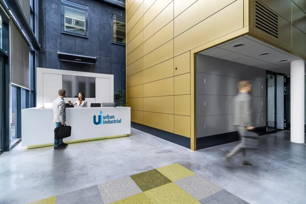 Moderne receptieruimte van Urban Industrial aan de Laarderhoogtweg met een balie, medewerker en bezoekers.