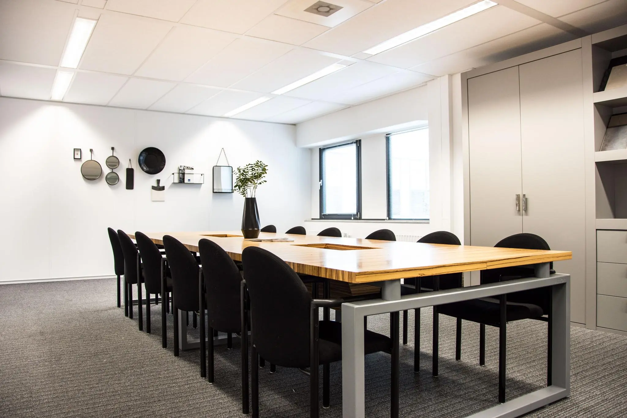 Vergaderruimte aan de Meidoornkade met een lange houten tafel, zwarte stoelen en moderne wanddecoratie.